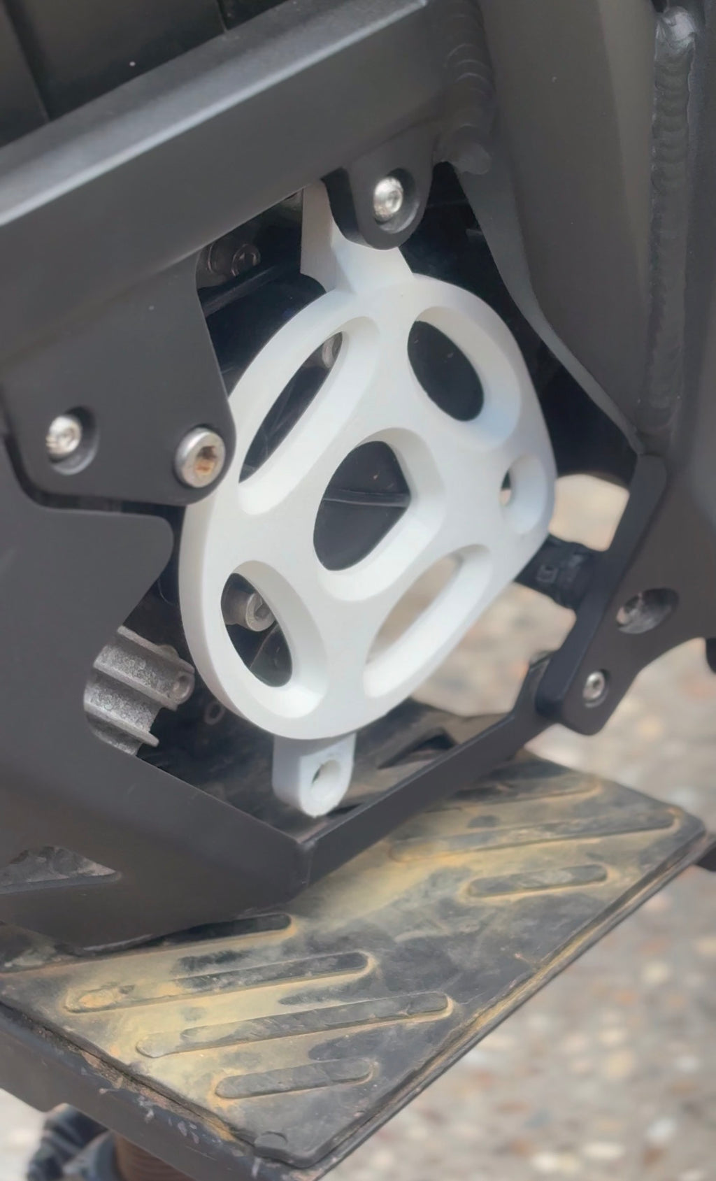 Close-up of a mechanical component with a white gear on a black metal frame.