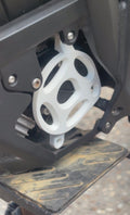 Close-up of a mechanical component with a white gear on a black metal frame.